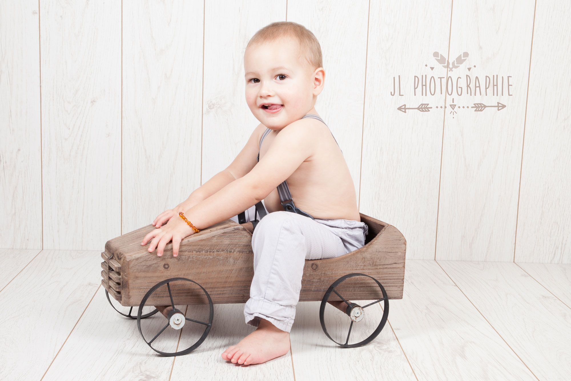 photographie d bébé assis dans une voiture en bois