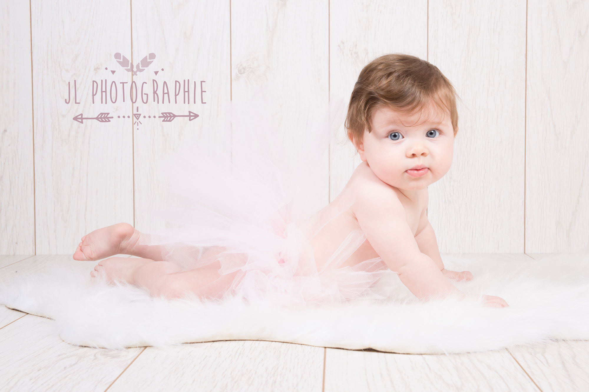 photographie d'un bébé allonge sur le ventre en tutu rose