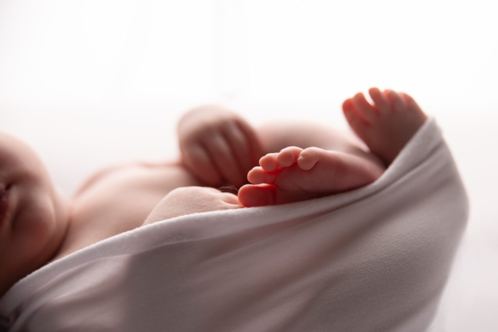 Séance photo nouveau né pieds de bébé en studio dans l’Oise emmailloté sur le dos