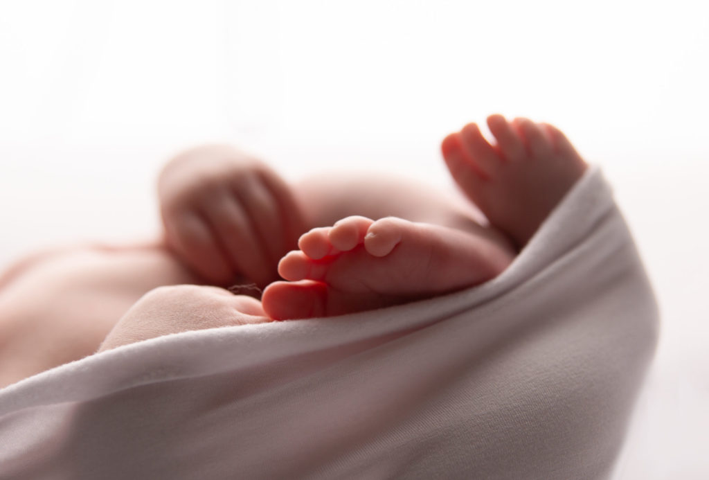 Séance photo nouveau né pieds de bébé en studio dans l’Oise emmailloté sur le dos