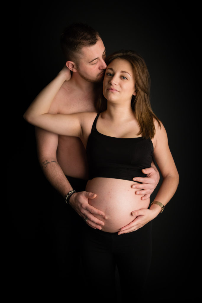 Photographie de grossesse en studio et en couple sur fond noir