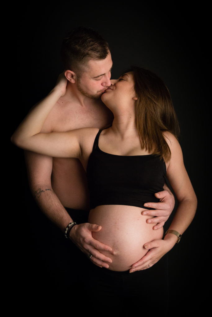 Photographie de grossesse en studio et en couple sur fond noir