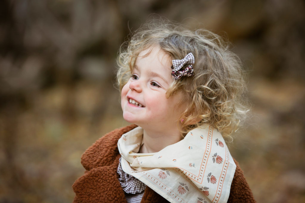 Petite fille blonde aux cheveux bouclés avec un foulard en extérieur dans la forêt dans l’Oise