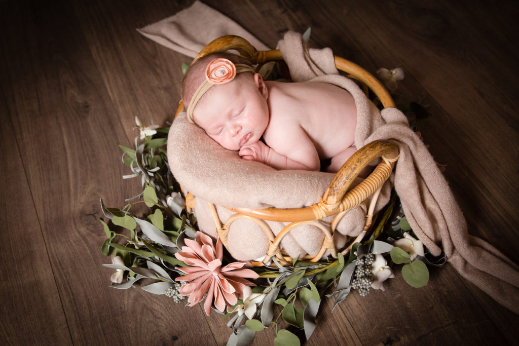 Séance photo nouveau né fille en studio dans l’Oise positionnée dans un panier entourée de fleur