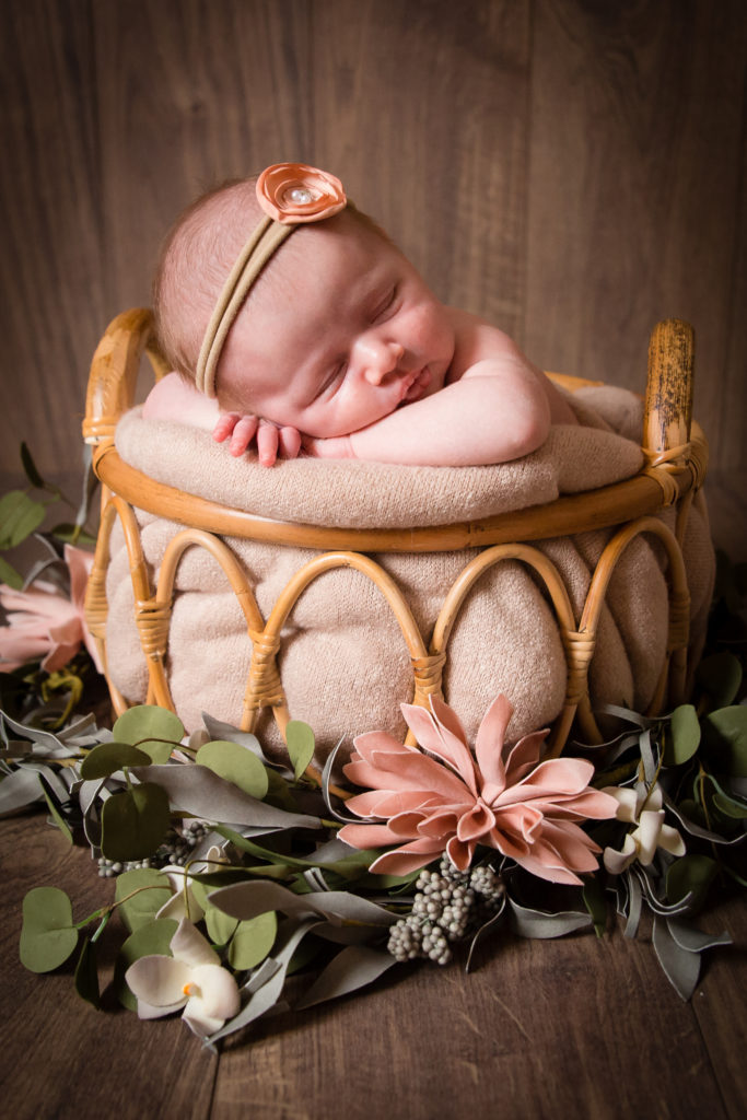 Séance photo nouveau né fille en studio dans l’Oise positionnée dans un panier entourée de fleur