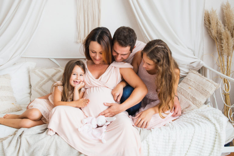 Shooting photo grossesse en studio en famille assis dans un decors bohème
