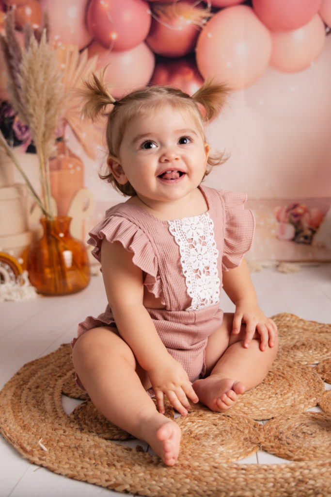 Photographie de bébé dans un decors d’anniversaire style bohème dans les tons rose