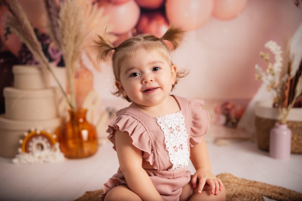 Photographie de bébé dans un decors d’anniversaire style bohème dans les tons rose