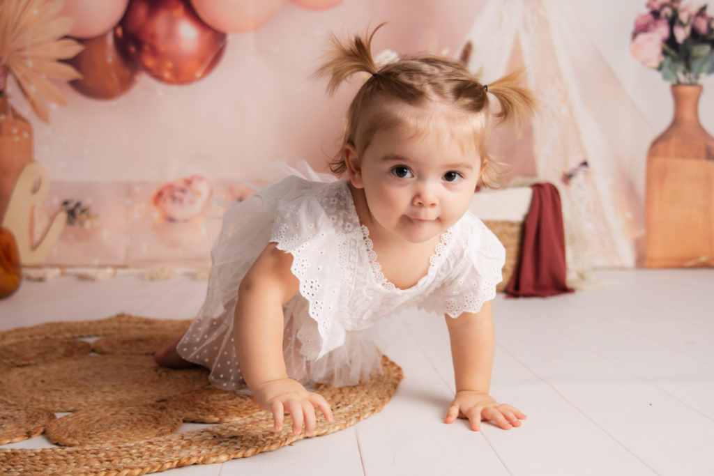 Photographie de bébé dans un decors d’anniversaire style bohème dans les tons rose