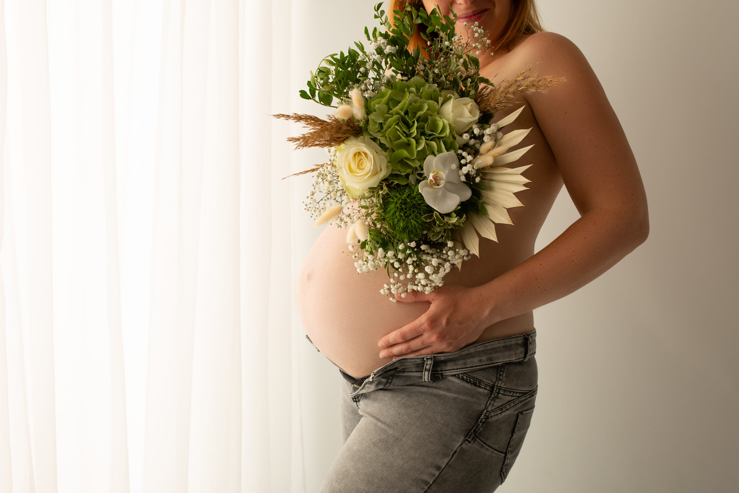 Séance photo grossesse en studio femme enceinte avec un bouquet de fleur