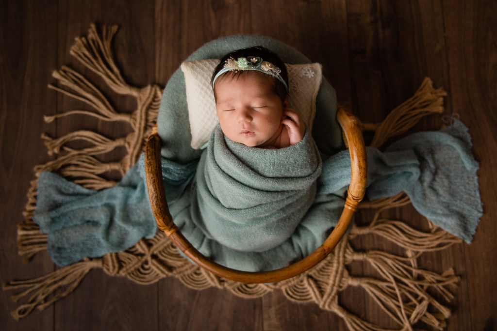 Séance photo nouveau né fille en studio dans l’Oise positionnée dans un panier couleur vert