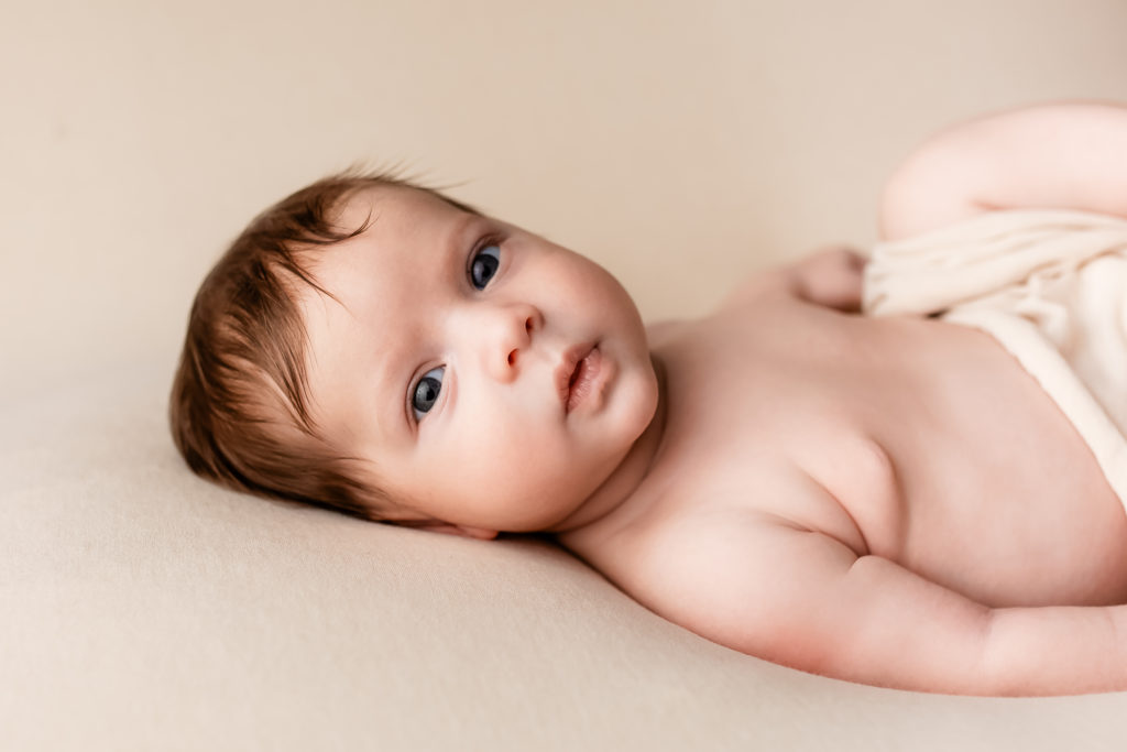 Séance photo en studio de nouveau-né dans l’Oise bébé posé sur une couverture beige