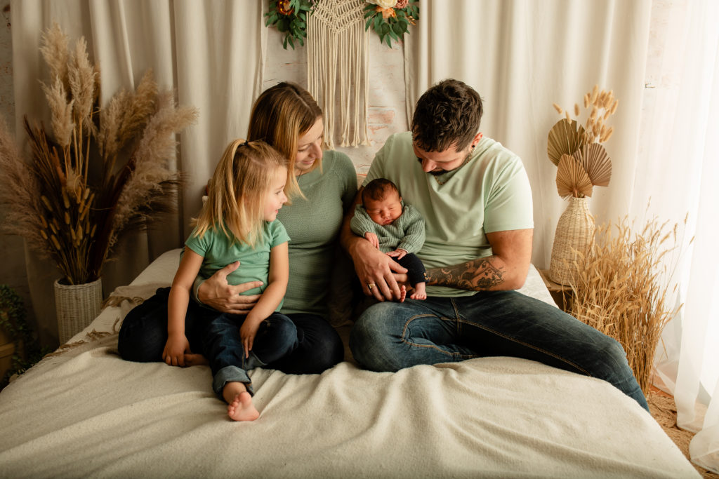 Photographie de famille avec un nouveau né en studio sur un décor bohème