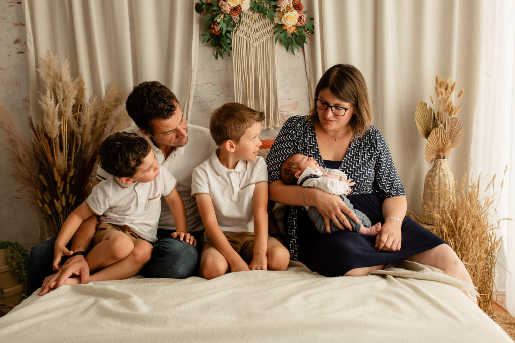 Photographie de famille avec un nouveau né en studio sur un décor bohème