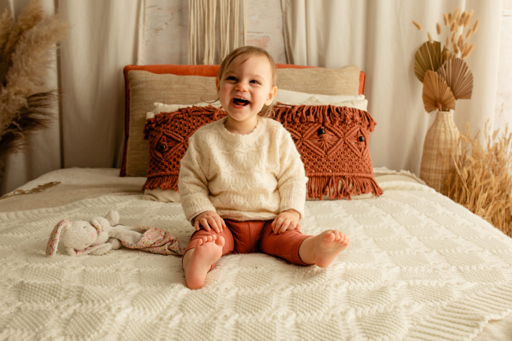 Séance photo de bébé en studio sur un lit décor bohème