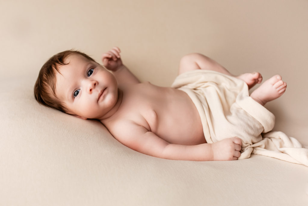Séance photo en studio de nouveau-né dans l’Oise bébé posé sur une couverture beige