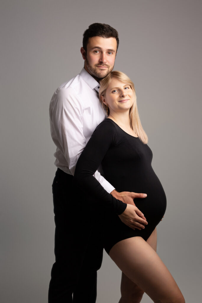 Photo professionnelle de grossesse, future maman en studio avec lumière douce et décor minimaliste.
