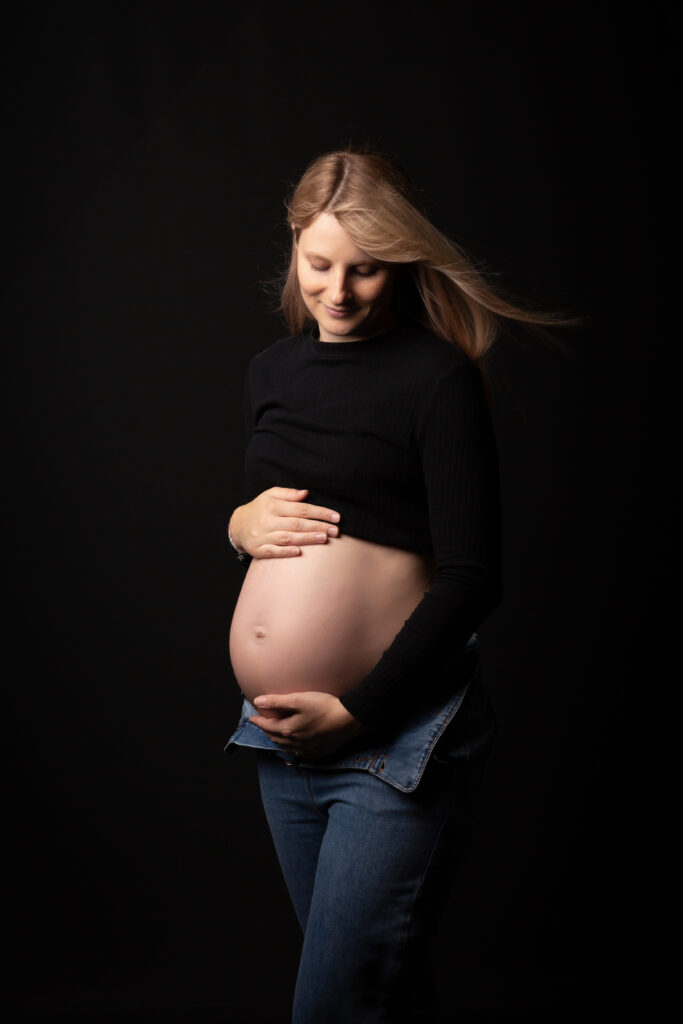 Séance photo de grossesse en studio, portrait intime d'une future maman rayonnante.